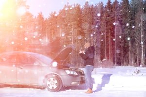 Man standing in front of broken car in winter in toronto