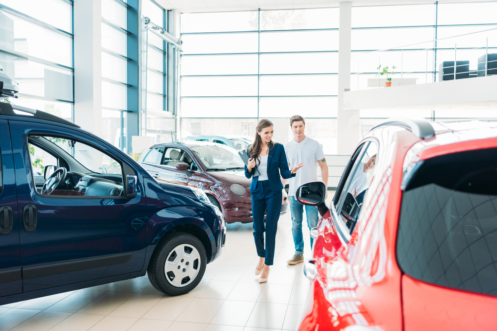 Young man at a car dealership, shopping for a new or used vehicle. 